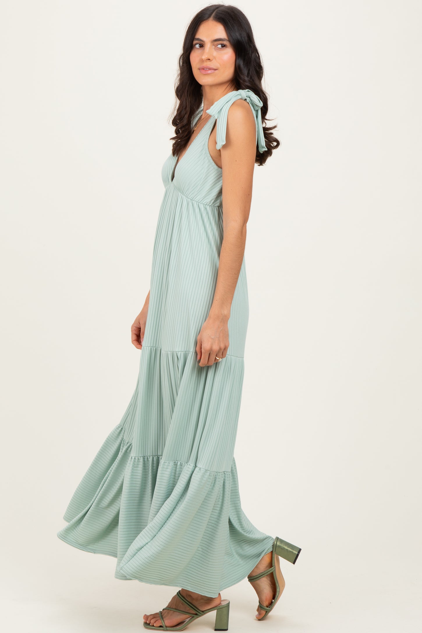 woman wearing a mint green maxi dress with tie shoulder straps and ruffled hemline