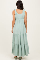 woman wearing a light green striped maxi dress with tie shoulder straps and a tiered skirt, viewed from the back