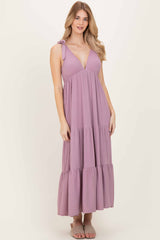 woman wearing a lavender maxi dress with a deep v-neck and tiered ruffle hem, styled with a shoulder tie detail