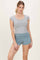 woman wearing a gray fitted short sleeve top and teal ruched athletic shorts