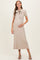 woman wearing a beige ribbed maternity dress with a bow tie detail and holding her baby bump