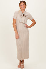 woman wearing a beige ribbed midi dress with short sleeves and a bow detail at the neckline