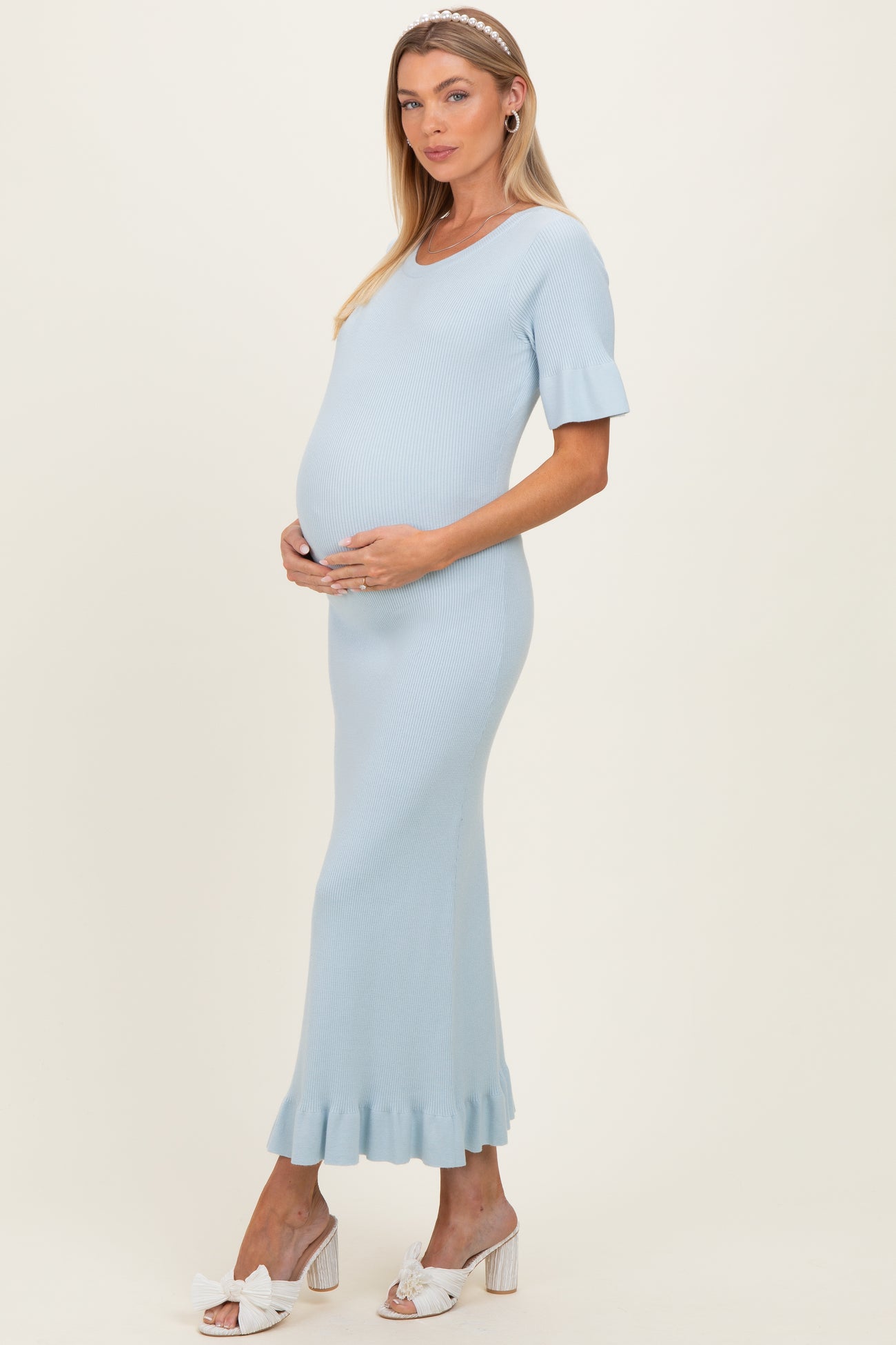 woman wearing a light blue ribbed maternity dress with short sleeves and a flounced hem, showing her baby bump