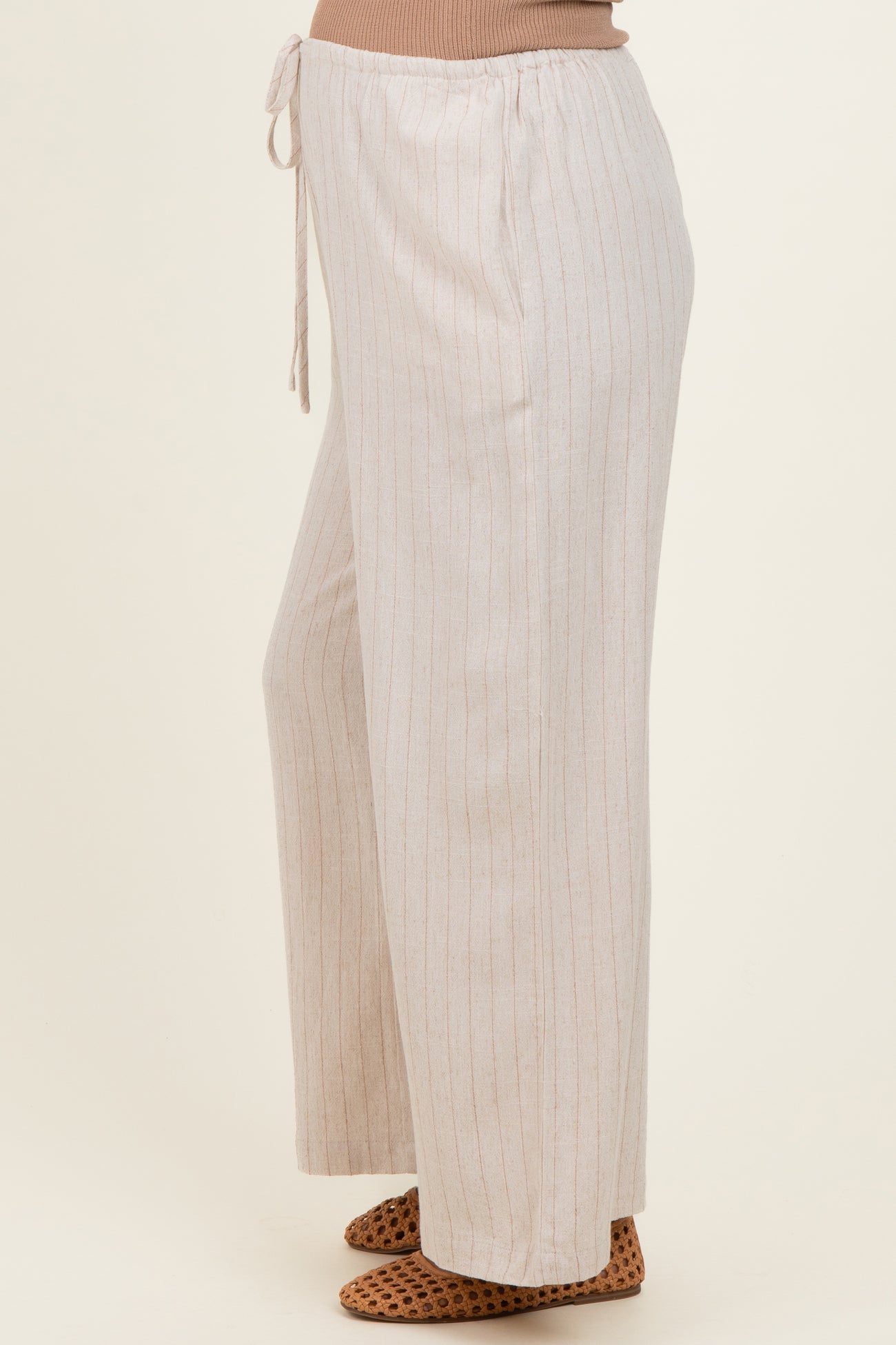 woman wearing light beige striped maternity pants with a drawstring waist