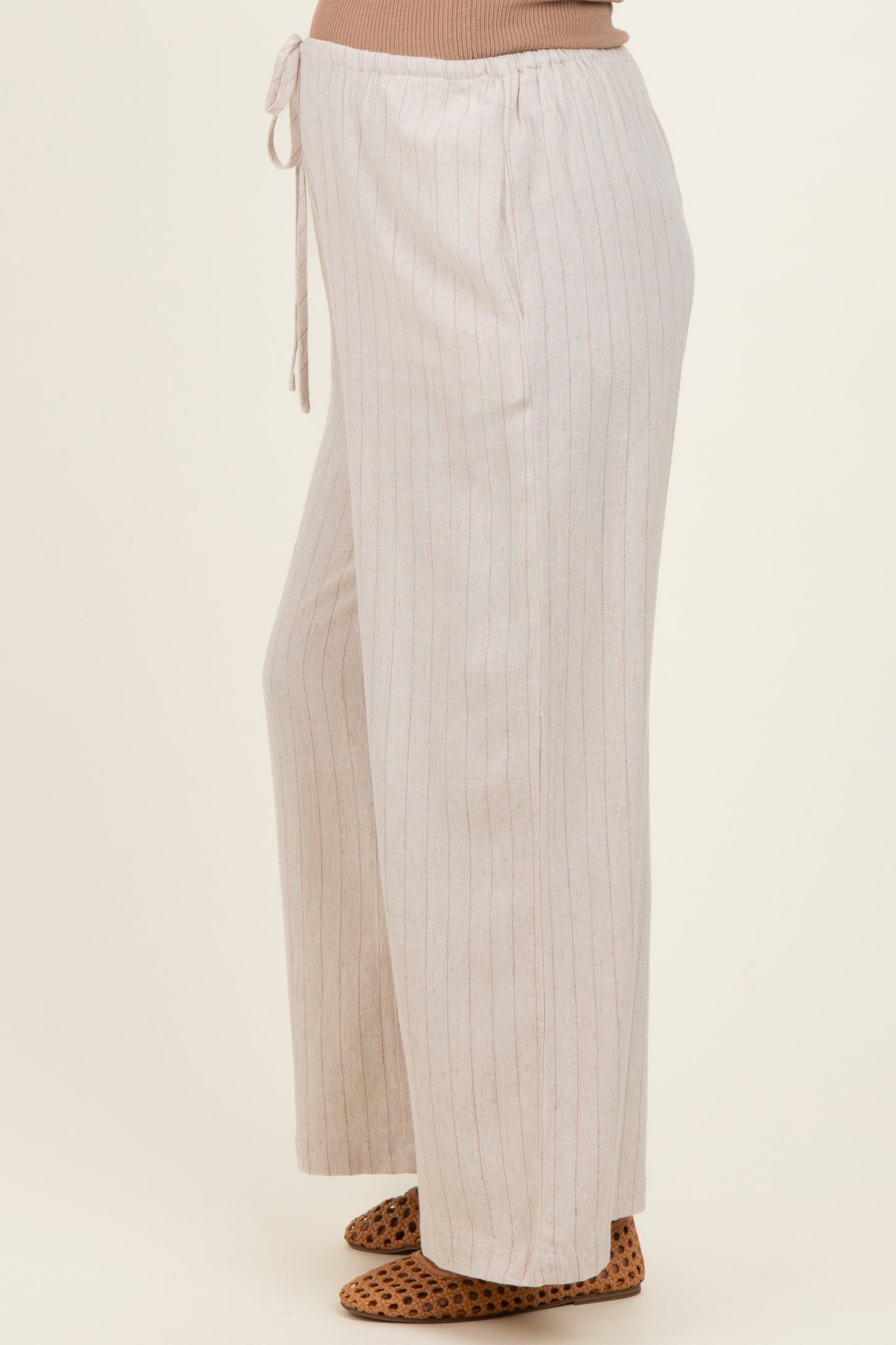 woman wearing light beige striped maternity pants with a drawstring waist