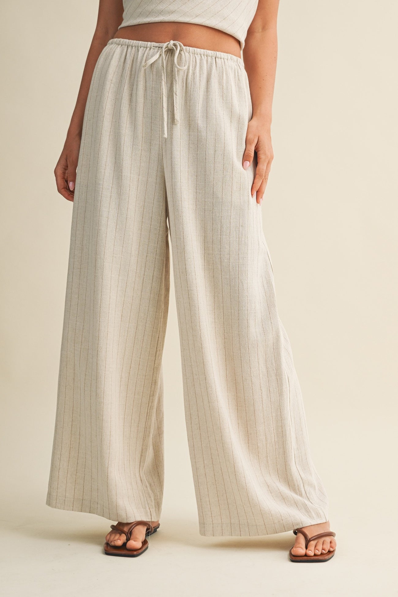 woman wearing beige striped wide-leg pants with an elastic waistband and drawstring detail