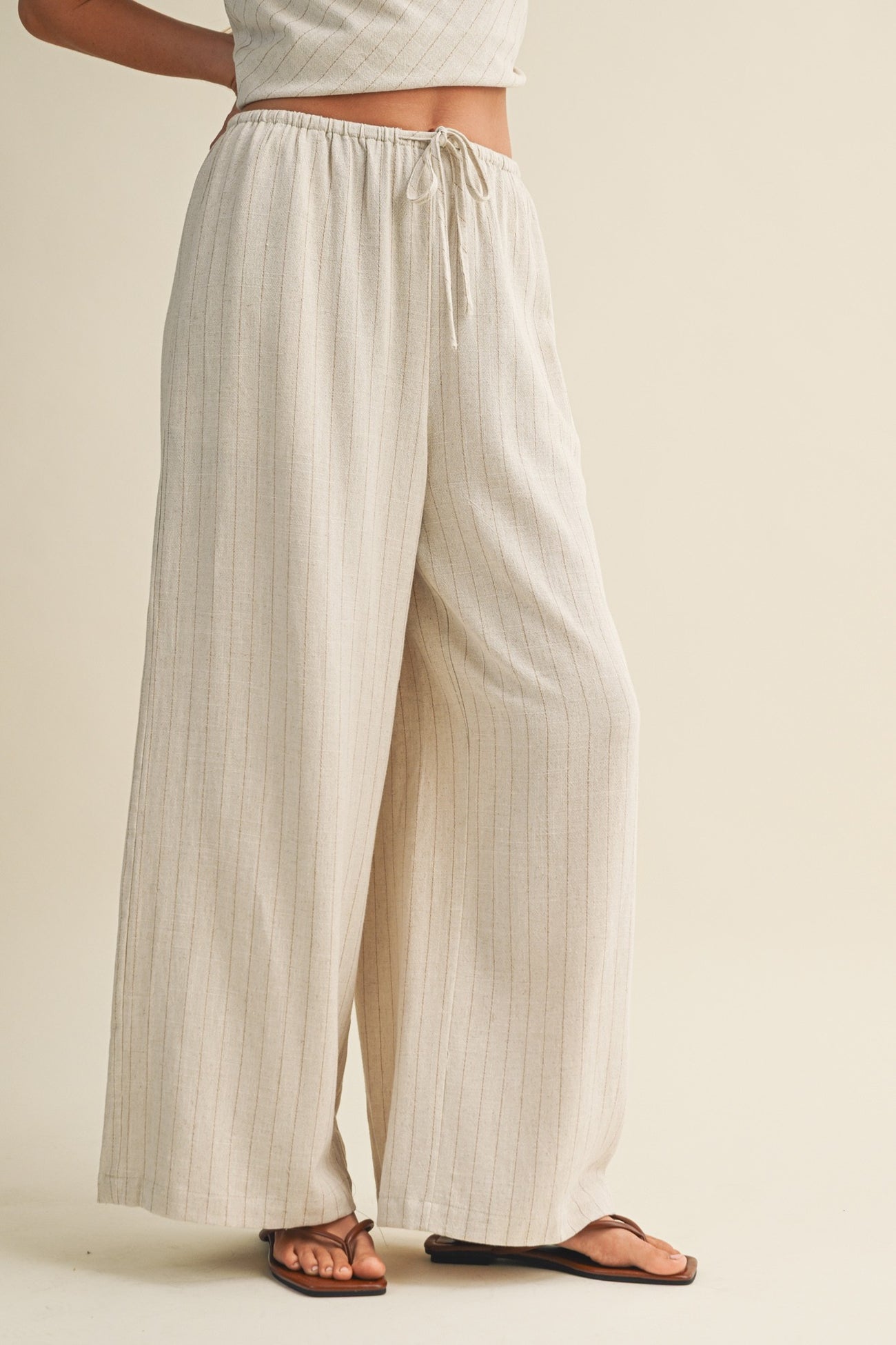 woman wearing beige striped wide-leg pants with an elastic waistband and drawstring, paired with a matching top