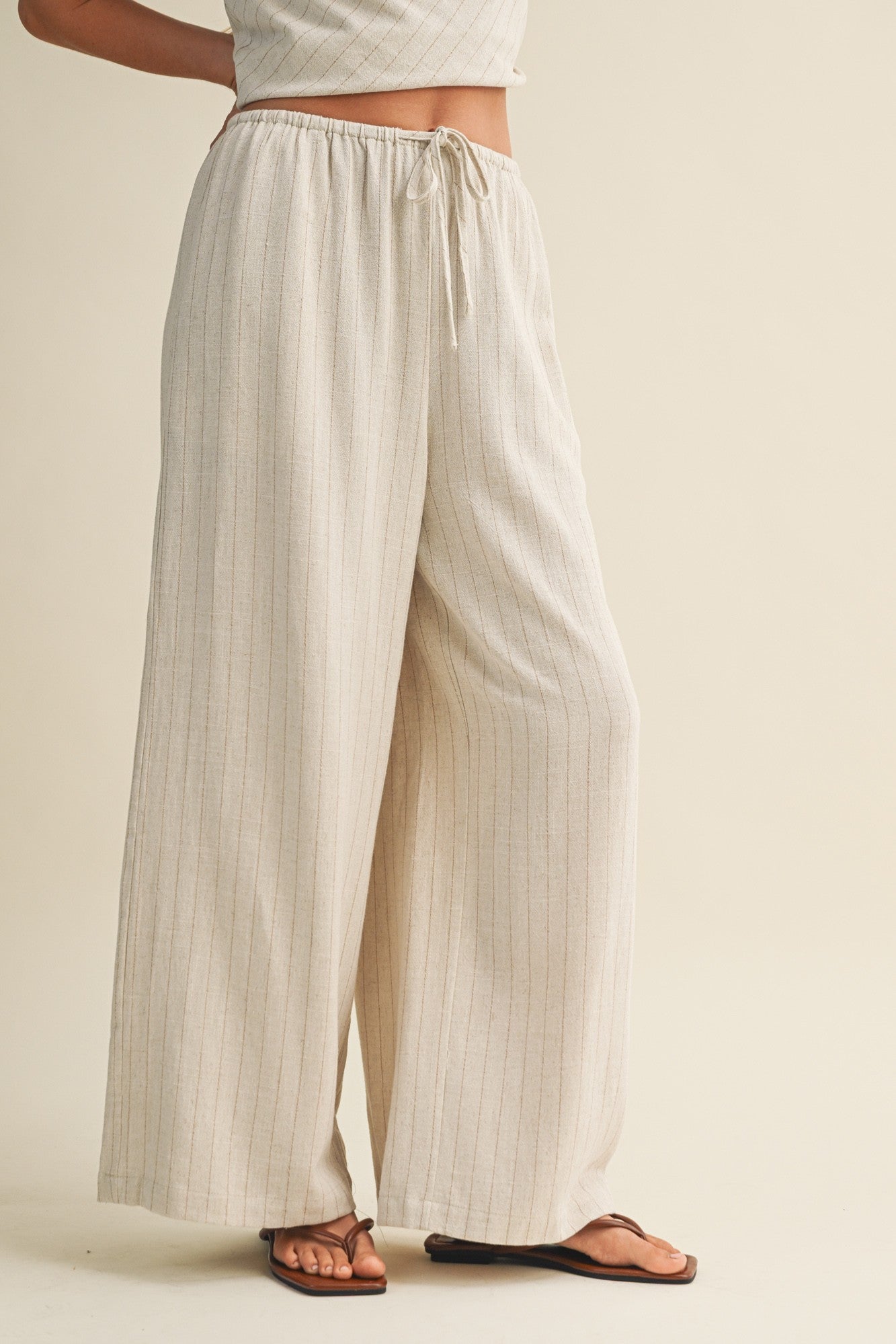 woman wearing beige striped wide-leg pants with an elastic waistband and drawstring, paired with a matching top