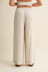 woman wearing beige high-waisted wide-leg pants with vertical stripes, viewed from the back
