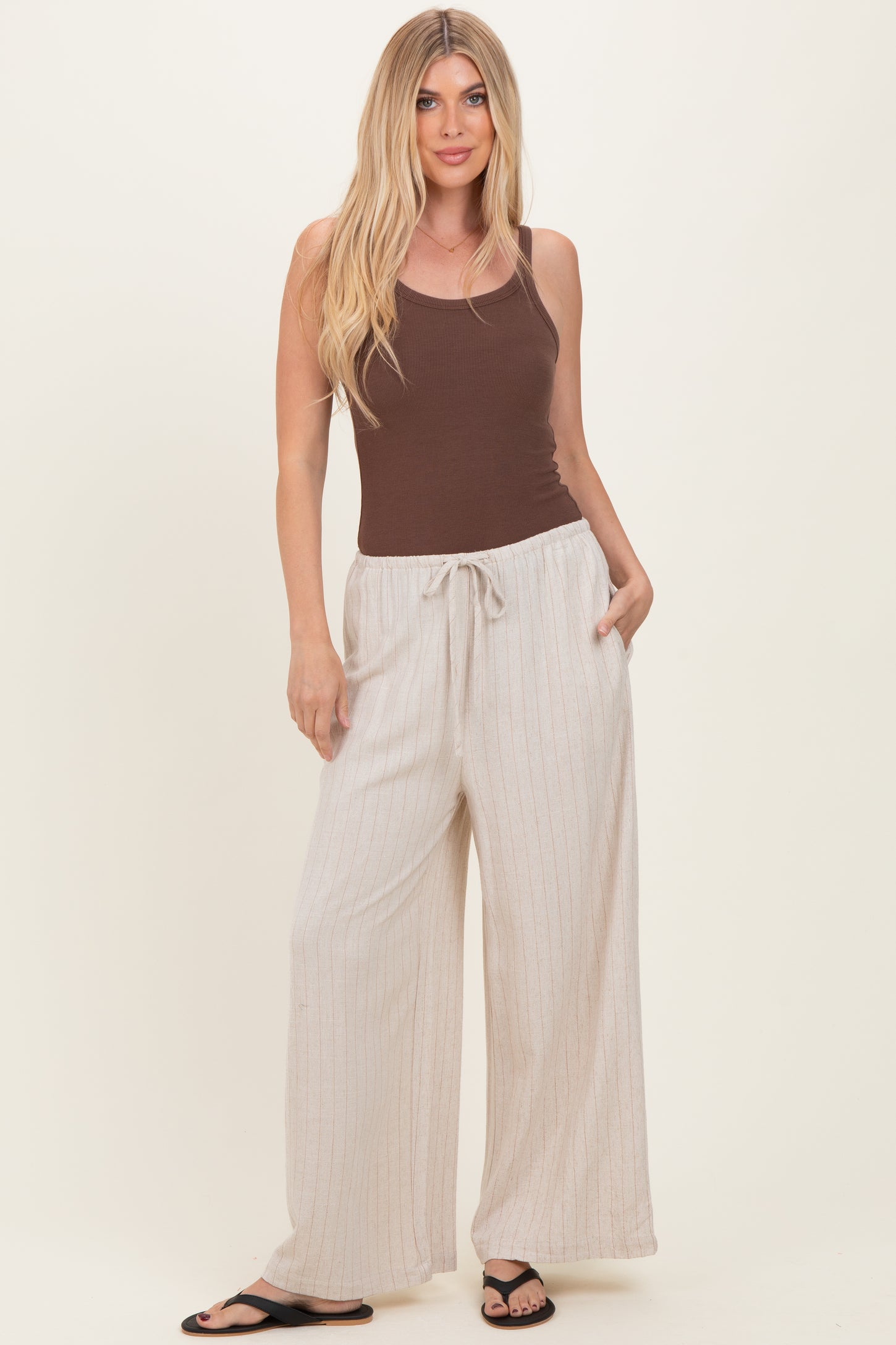 woman wearing a brown tank top and cream striped wide-leg pants with a drawstring waist