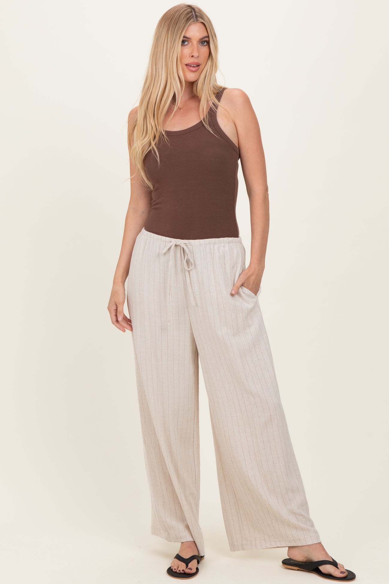 woman wearing a brown tank top and beige striped wide-leg pants with pockets and drawstring waist