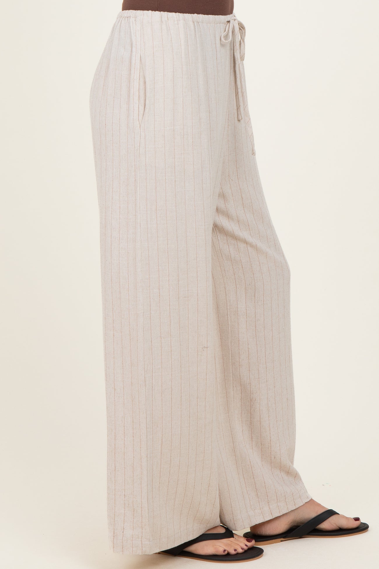 woman wearing light beige striped wide-leg pants with drawstring waist and side pockets