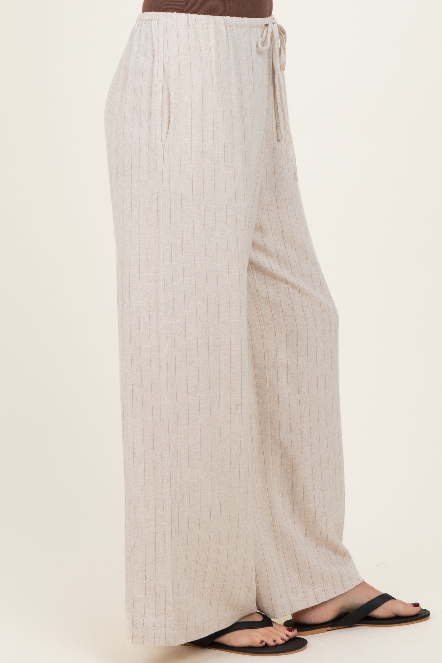 woman wearing light beige striped wide-leg pants with drawstring waist and side pockets