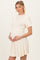 woman wearing a cream ribbed maternity dress with short sleeves and a flared skirt, holding her baby bump