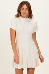 woman wearing a cream short sleeve ribbed sweater dress with a flared skirt
