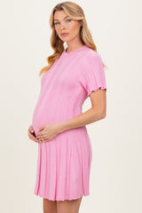 woman wearing a pink short sleeve knitted maternity dress and holding her baby bump