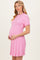 woman wearing a pink short sleeve knitted maternity dress and holding her baby bump