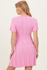 woman wearing a fitted pink ribbed short sleeve maternity dress with a flared hemline