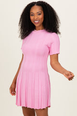 woman wearing a light pink short sleeve ribbed dress with a flared skirt and a round neckline