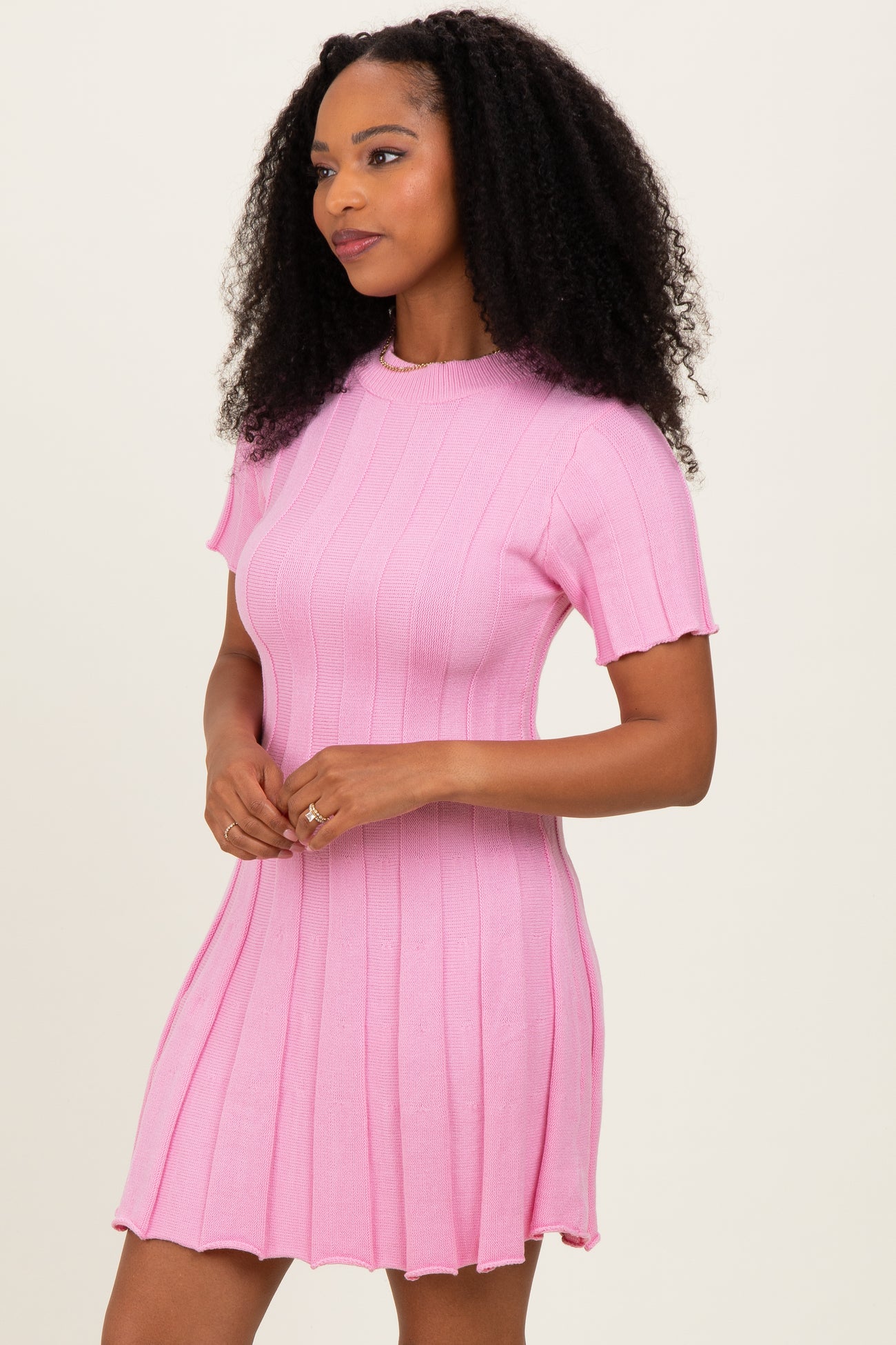 woman wearing a pink short sleeve ribbed knit dress with a flared hem