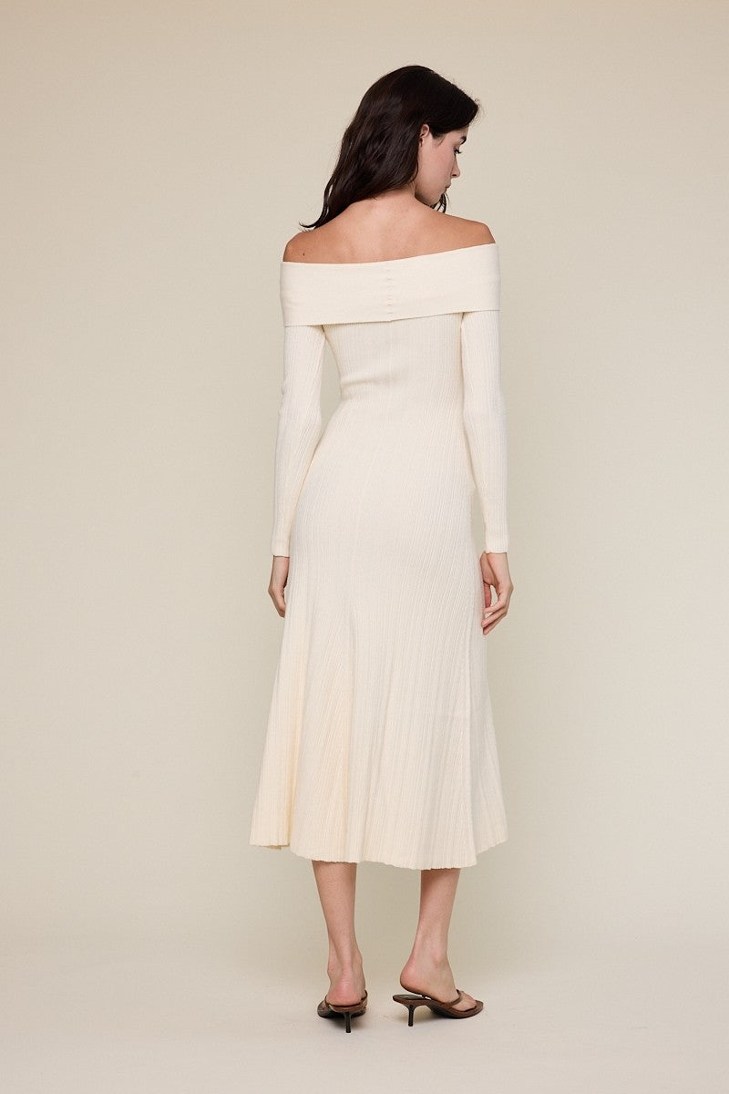 woman wearing a cream off-shoulder ribbed midi dress, showing the back and long sleeves, with a fitted bodice and flared skirt