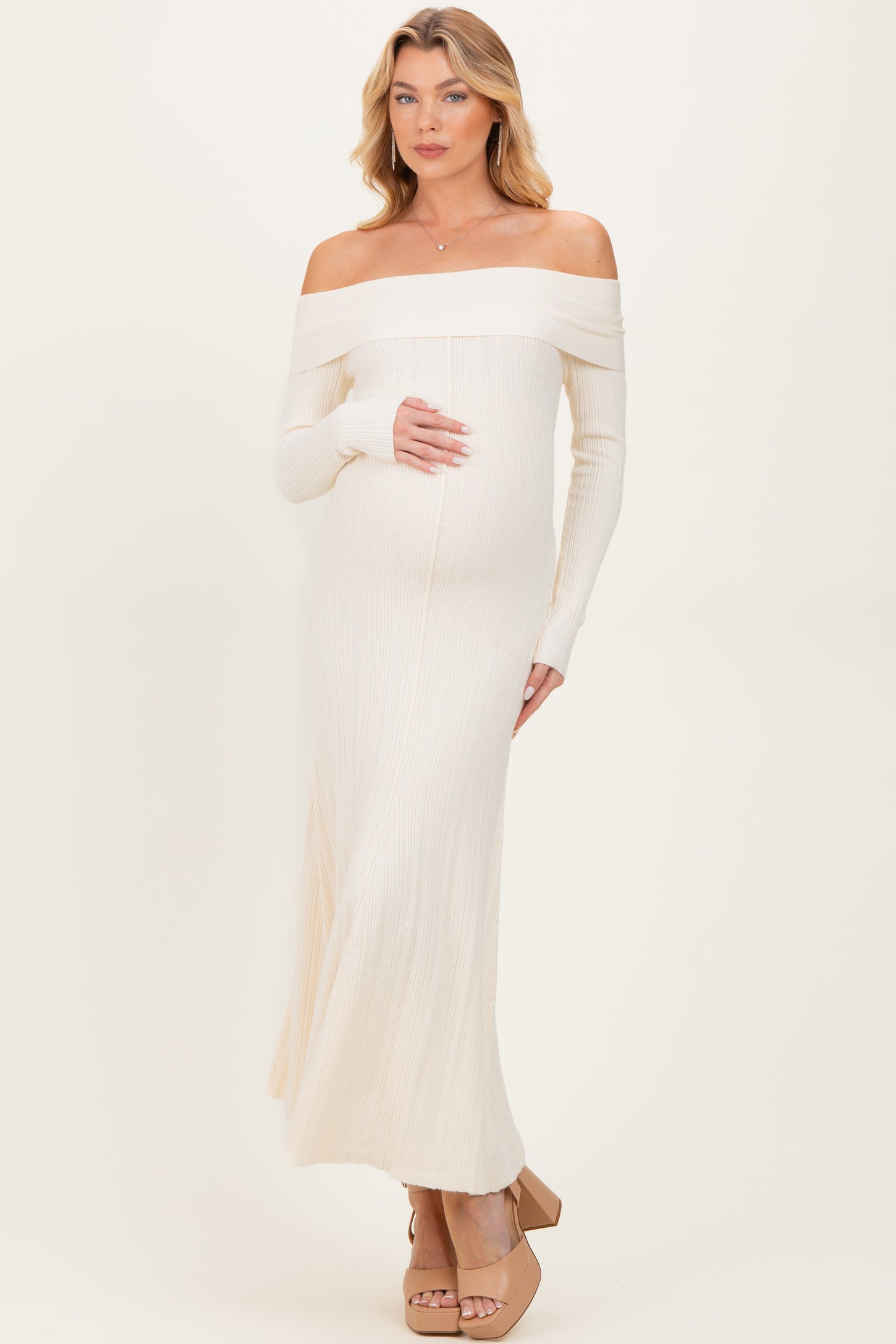 woman wearing an off-the-shoulder ribbed maternity dress in light beige, showcasing her baby bump