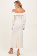 woman wearing a cream off-the-shoulder ribbed maternity dress with long sleeves and a flowing midi length