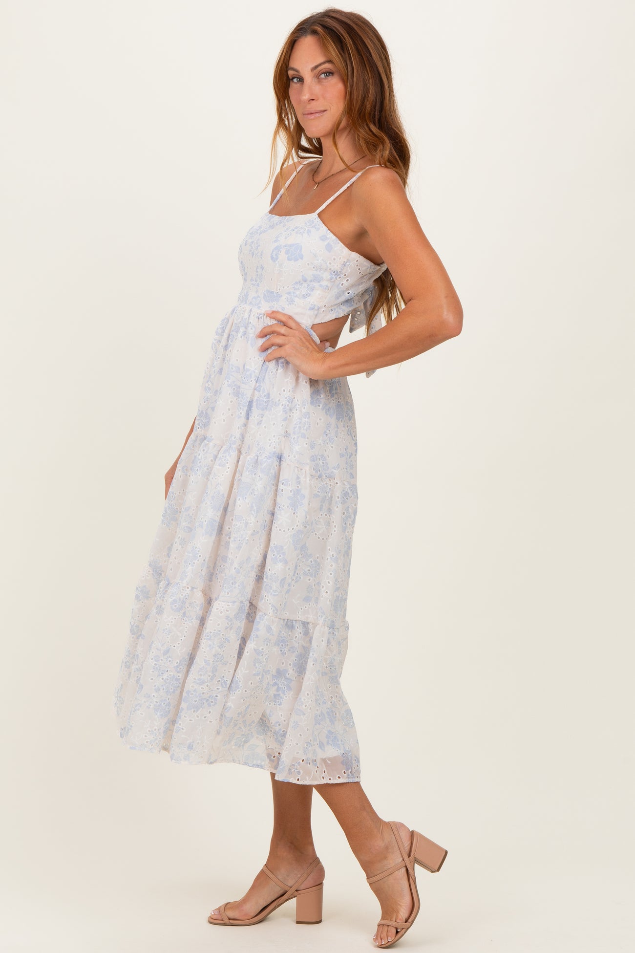 woman wearing a light blue floral tiered maxi dress with spaghetti straps and a flowing silhouette