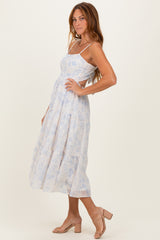 woman wearing a light blue floral tiered maxi dress with spaghetti straps and a flowing silhouette