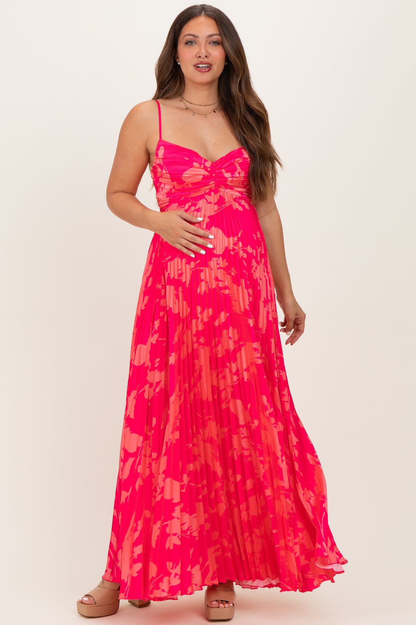 woman wearing a vibrant pink floral maternity maxi dress, showing her baby bump