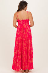 woman wearing a pink and coral patterned maternity maxi dress with a smocked bodice and pleated skirt, showing a baby bump