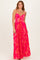 woman wearing a bright pink pleated maxi dress with a twist bodice and spaghetti straps
