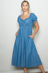 woman wearing a light blue denim midi dress with puff sleeves and pockets
