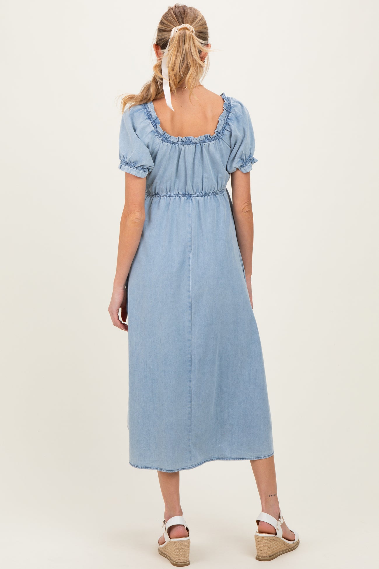 woman wearing a light blue maternity maxi dress with puff sleeves and a cinched waist, styled for summer