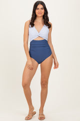 woman wearing a striped blue and white one-piece swimsuit with a high-waisted navy bottom