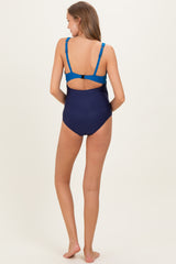 woman wearing a navy blue maternity swimsuit with adjustable blue straps and a back cutout design
