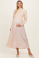 woman wearing a cream ribbed maternity sweater and a flowing blush pink maternity maxi skirt, holding her baby bump