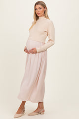 woman wearing a cream ribbed maternity sweater and a flowing blush pink maternity maxi skirt, holding her baby bump