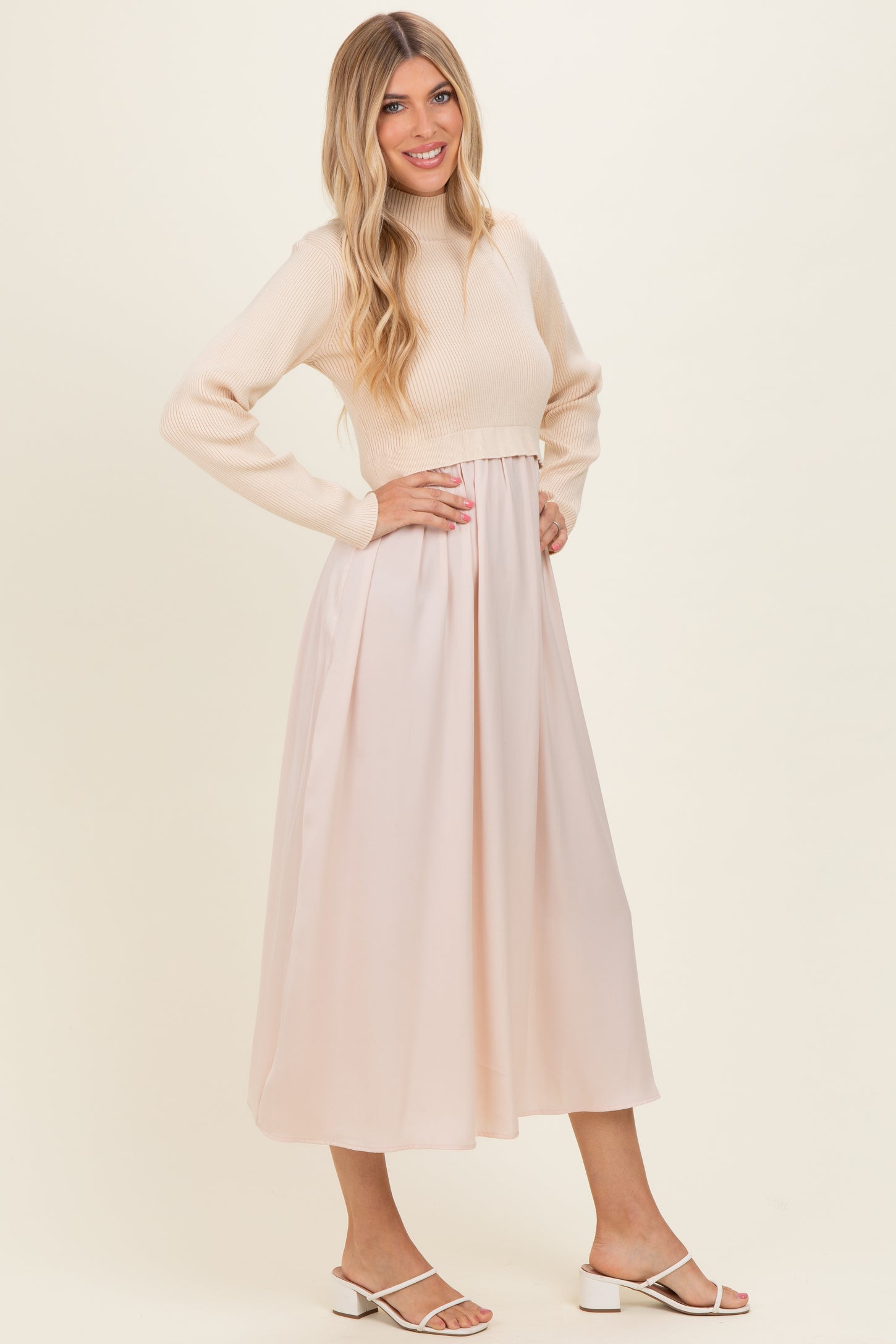 woman wearing a cream long sleeve ribbed top and a flowy blush pink midi skirt with a fitted waist