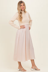 woman wearing a cream long sleeve ribbed top and a flowy blush pink midi skirt with a fitted waist