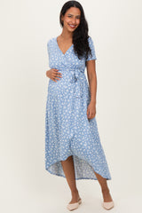 woman wearing a light blue maternity dress with white floral print and tie waist, showing her baby bump