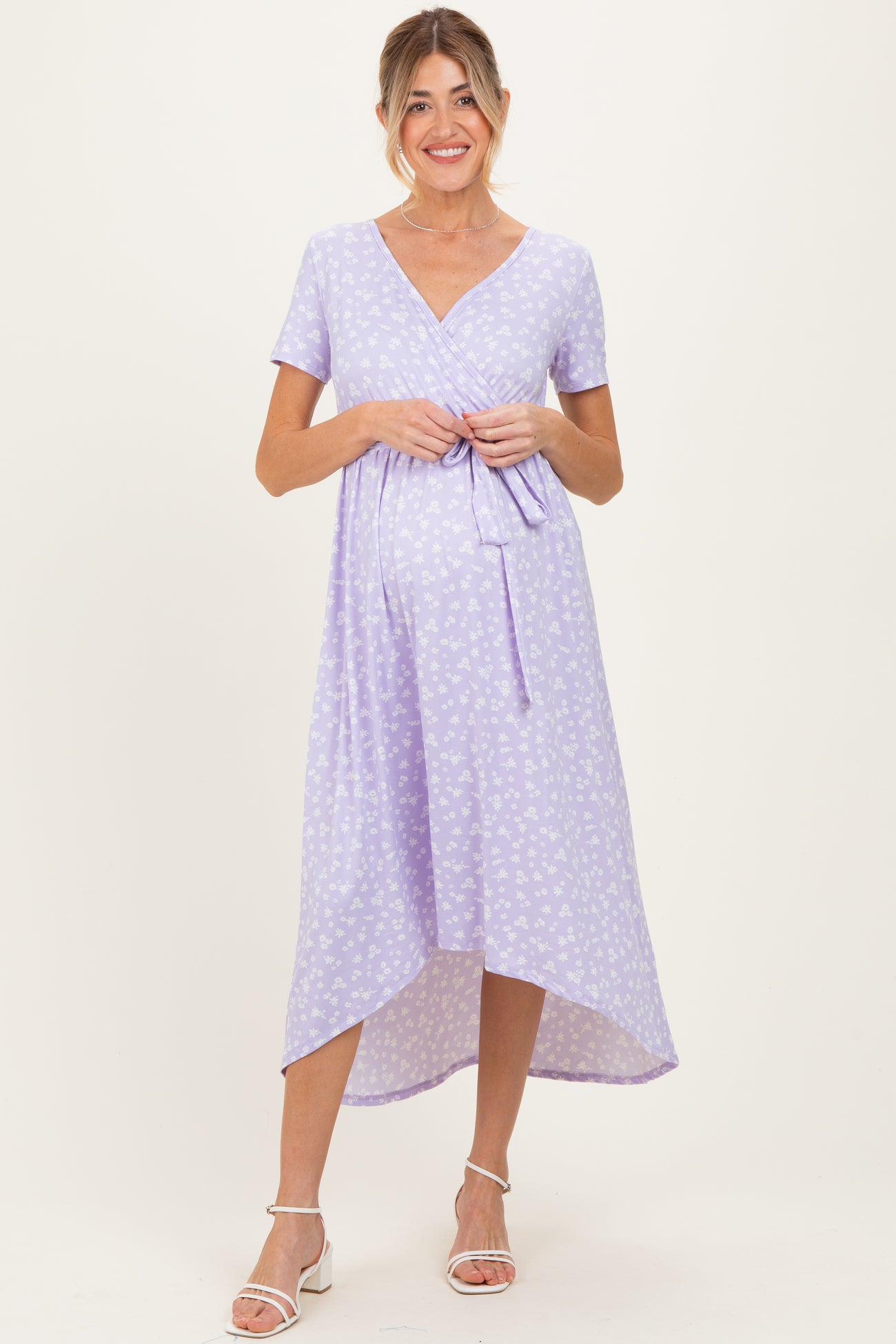 woman wearing a lavender floral maternity dress with a wrap tie and a high-low hem, showing her baby bump
