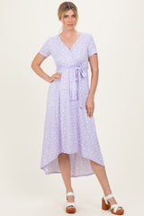woman wearing a lavender wrap dress with short sleeves and a high-low hem, styled with white block-heel sandals