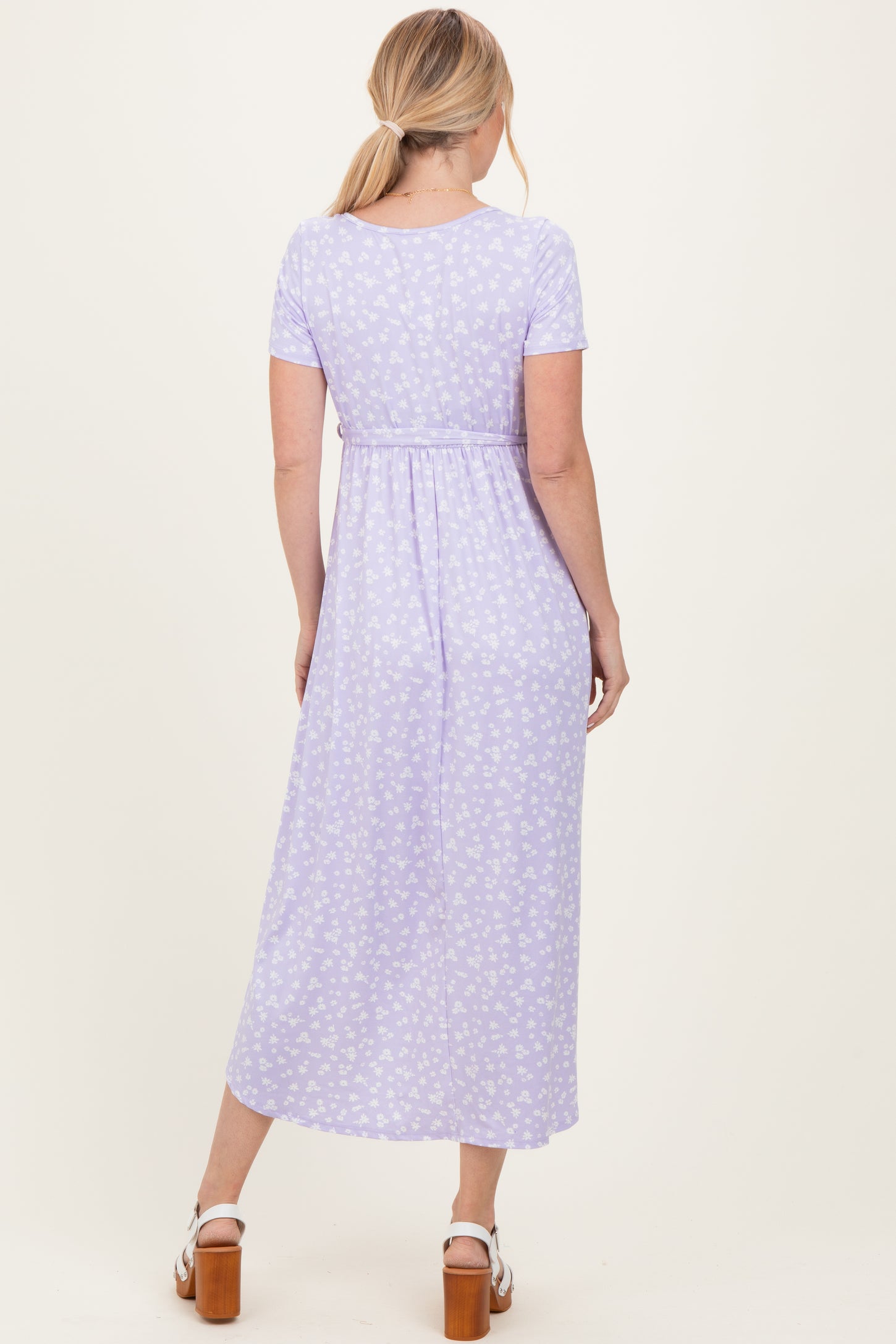 woman wearing a lilac floral maxi dress with short sleeves and a cinched waist, view from the back