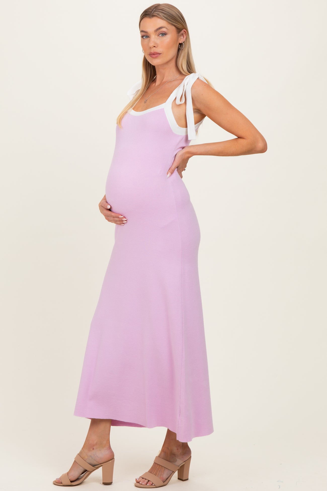 woman wearing a light pink maternity maxi dress with white tie straps and showing her baby bump
