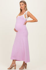 woman wearing a light pink maternity maxi dress with white tie straps and showing her baby bump