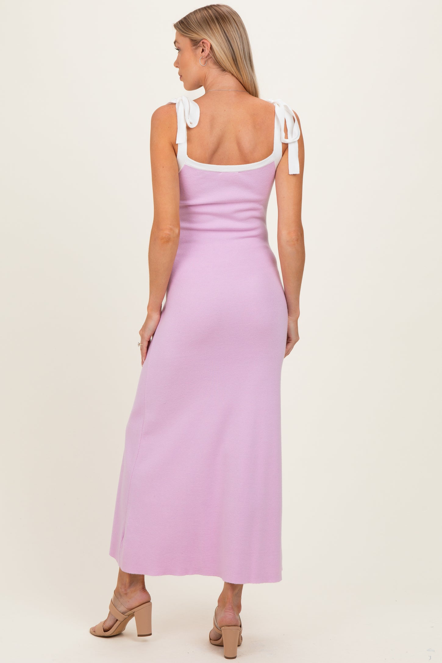 woman wearing a lilac maternity dress with white tie straps, featuring a fitted silhouette and a maxi length