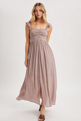 woman wearing a dusty mauve maxi dress with ruffled straps and a front slit