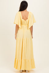 woman wearing a yellow maxi dress with flutter sleeves and a tiered design, shown from the back