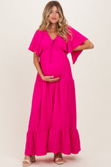 woman wearing a bright pink maternity maxi dress with a tie-front and layered sleeves, highlighting her baby bump